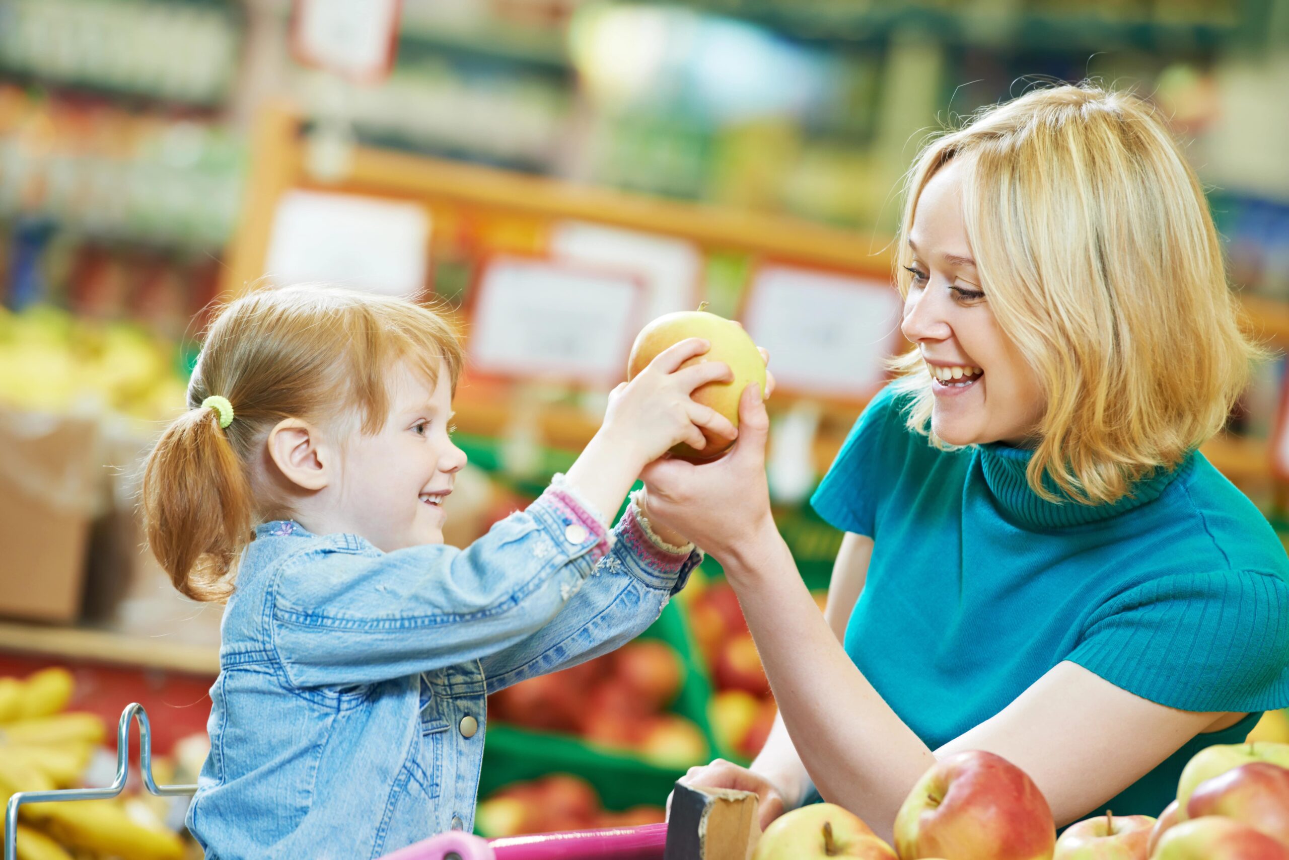 preschool daughter helping mom shop for apples