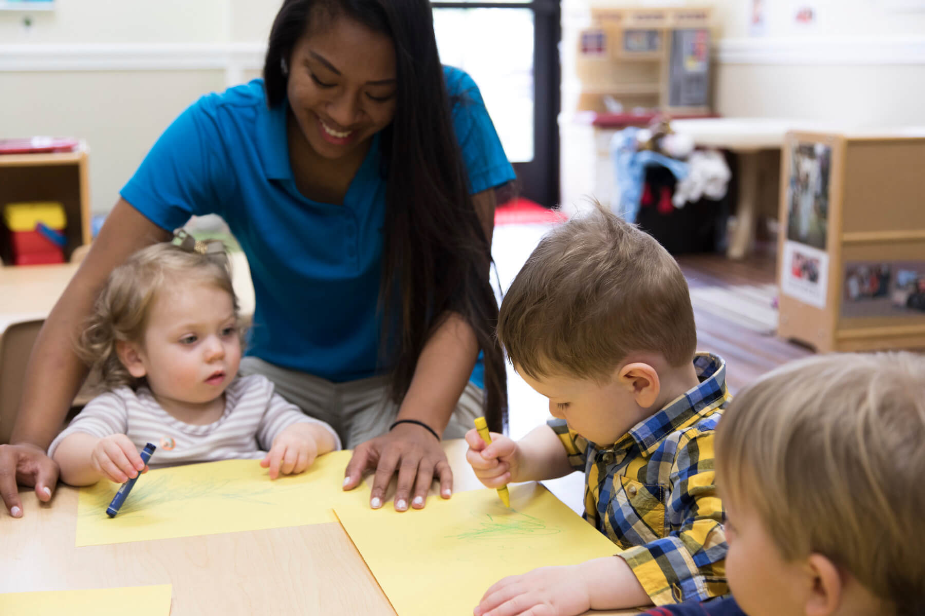 preschool teacher helping preschoolers with coloring activity