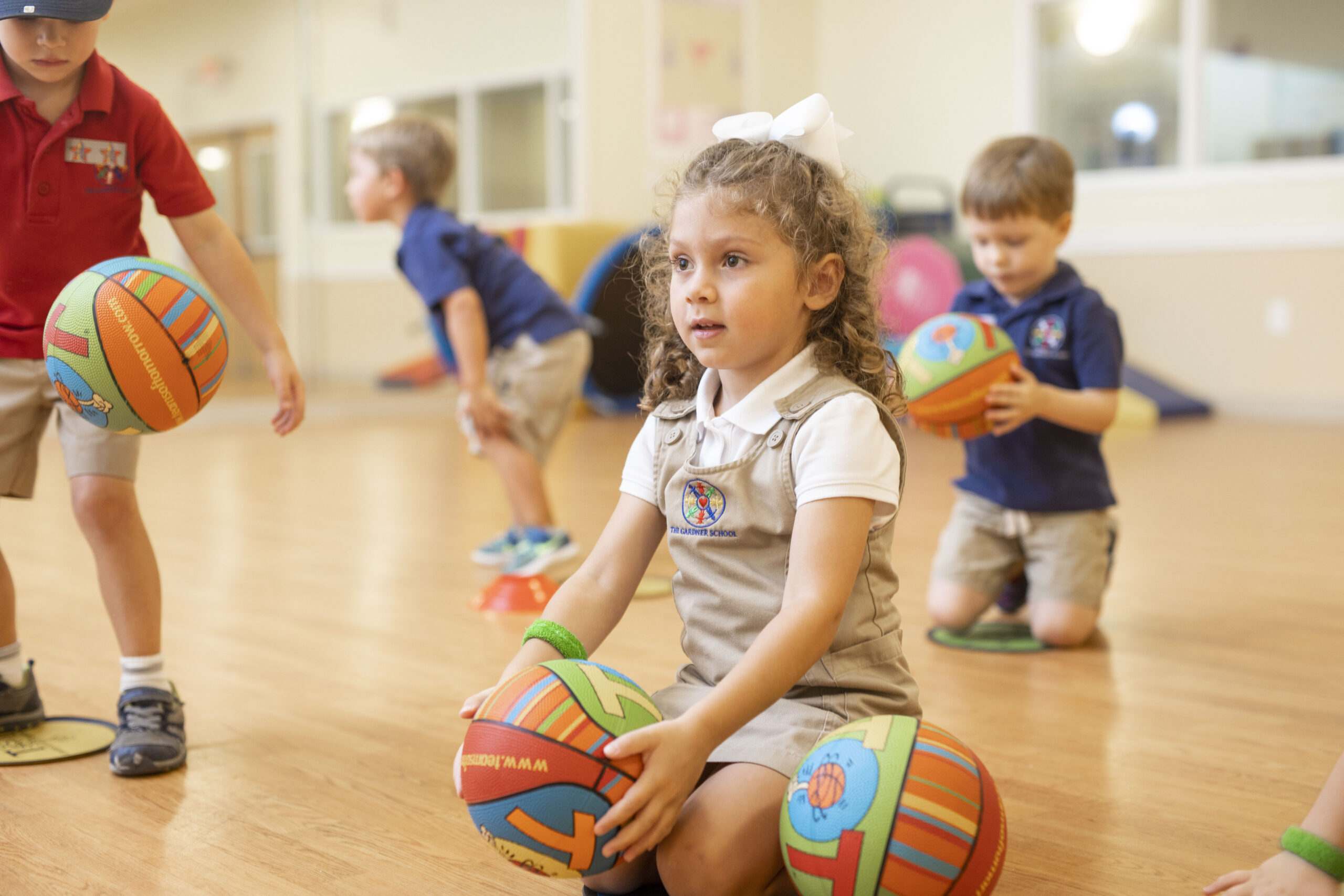 preschool girl in enrichment class holding a basketball