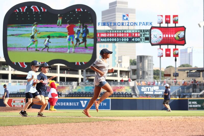 kids and adults running on baseball field