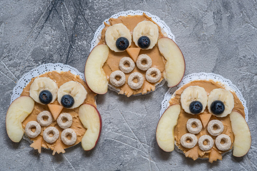 Funny owl snack with peanut butter and fruits on rice cake