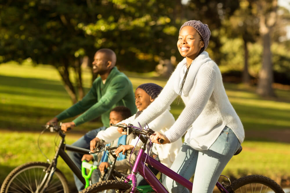 a mom, dad and child riding bikes together through a neighborhood