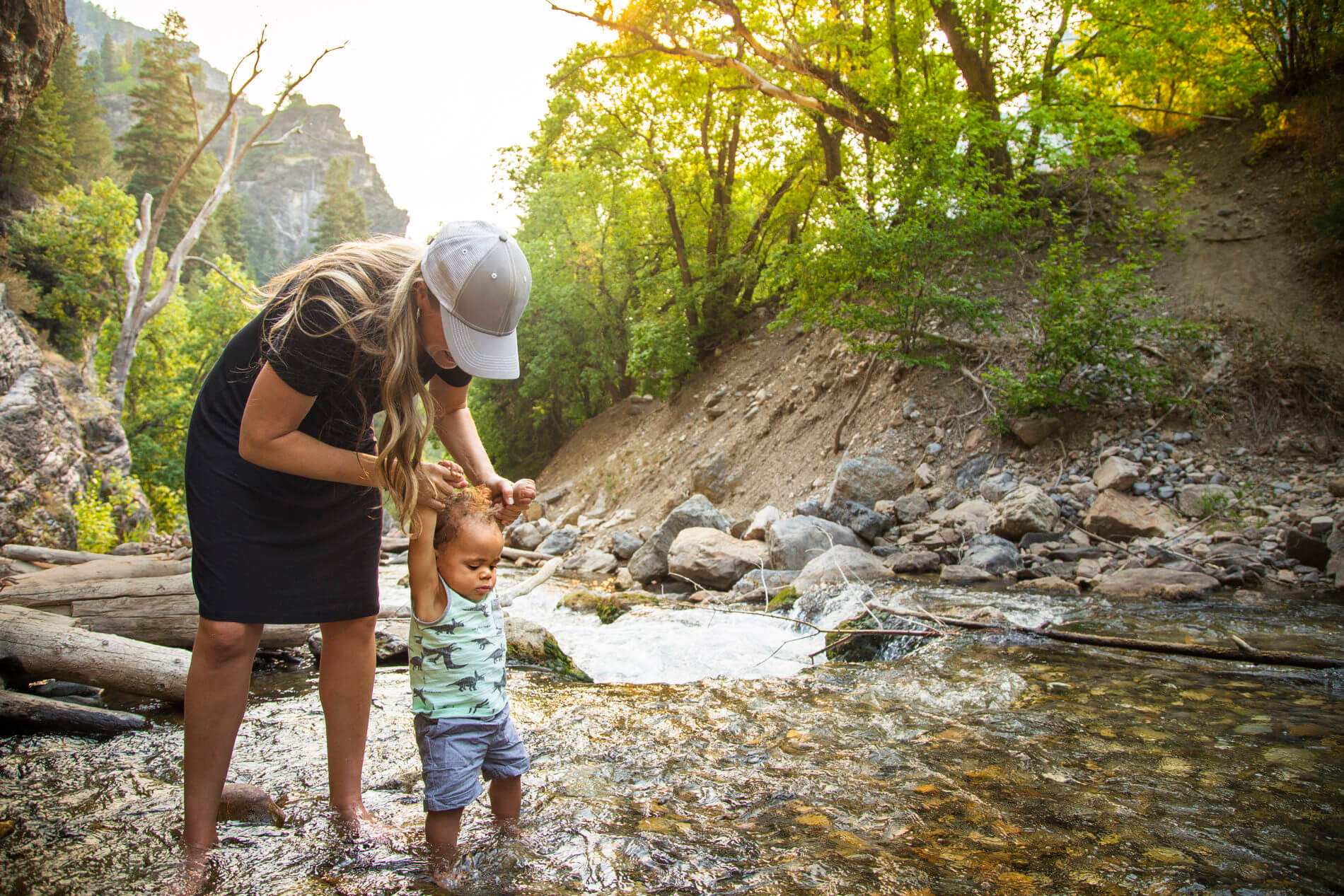 mother walking toddler through creek
