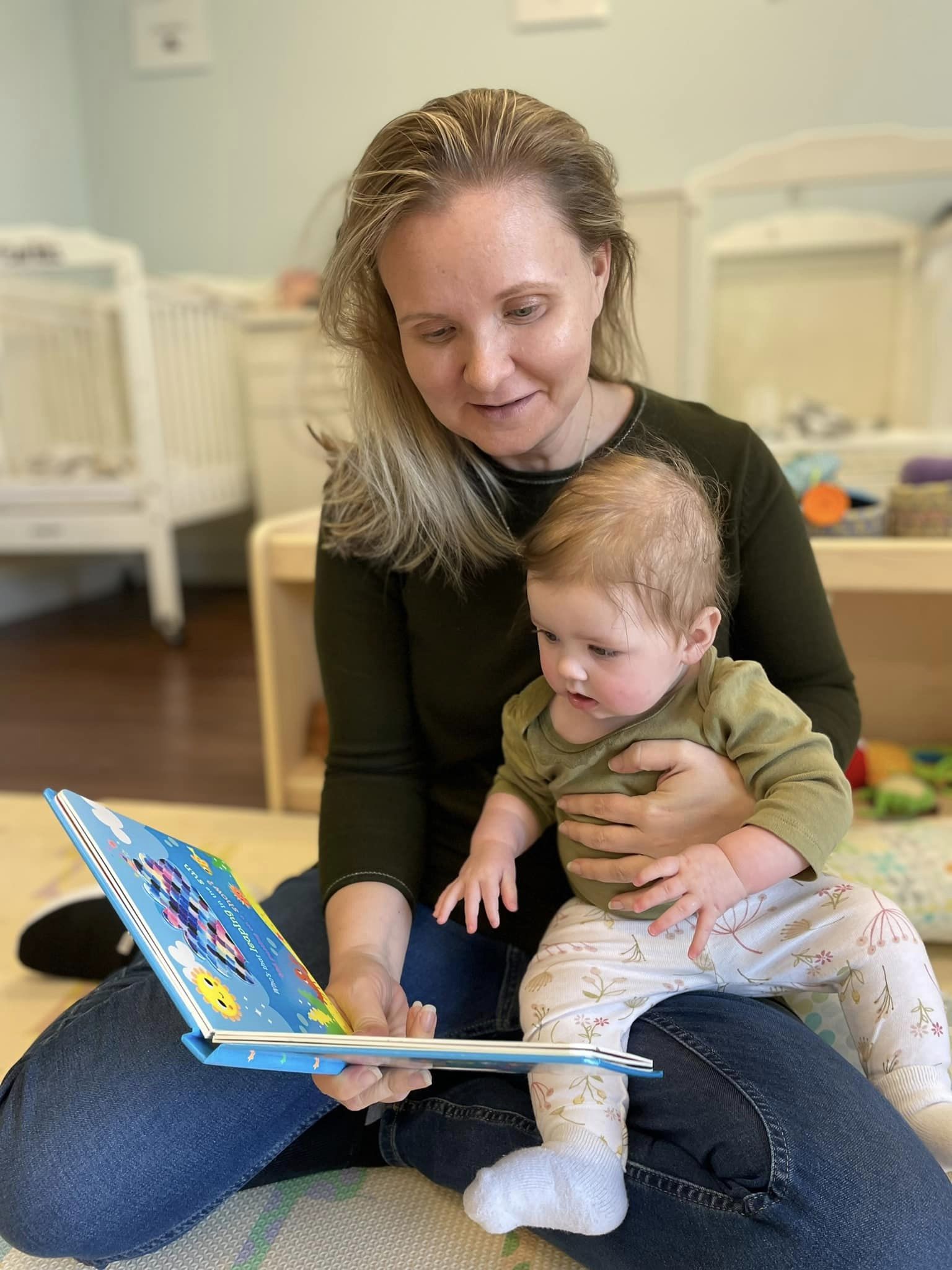 preschool teacher reading a book to baby