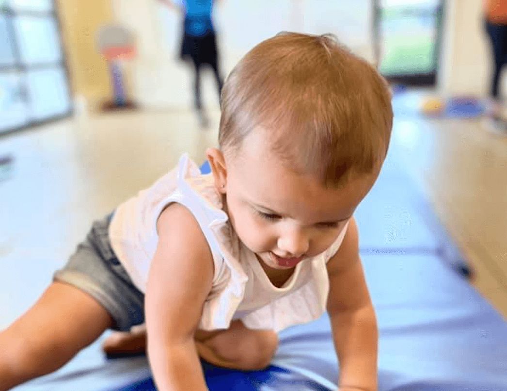 toddler crawling on gym mat at preschool