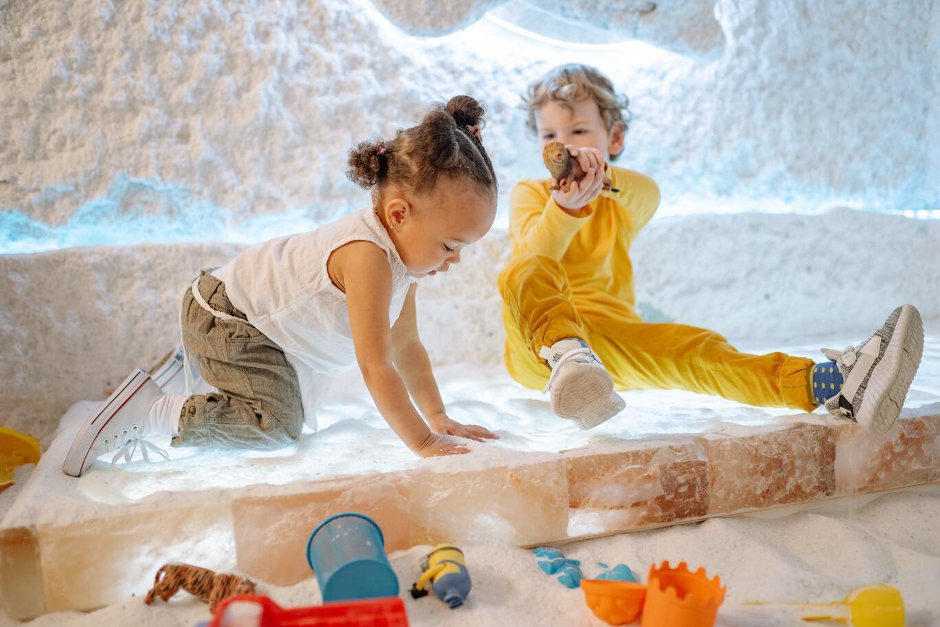 2 toddlers play with sand pit