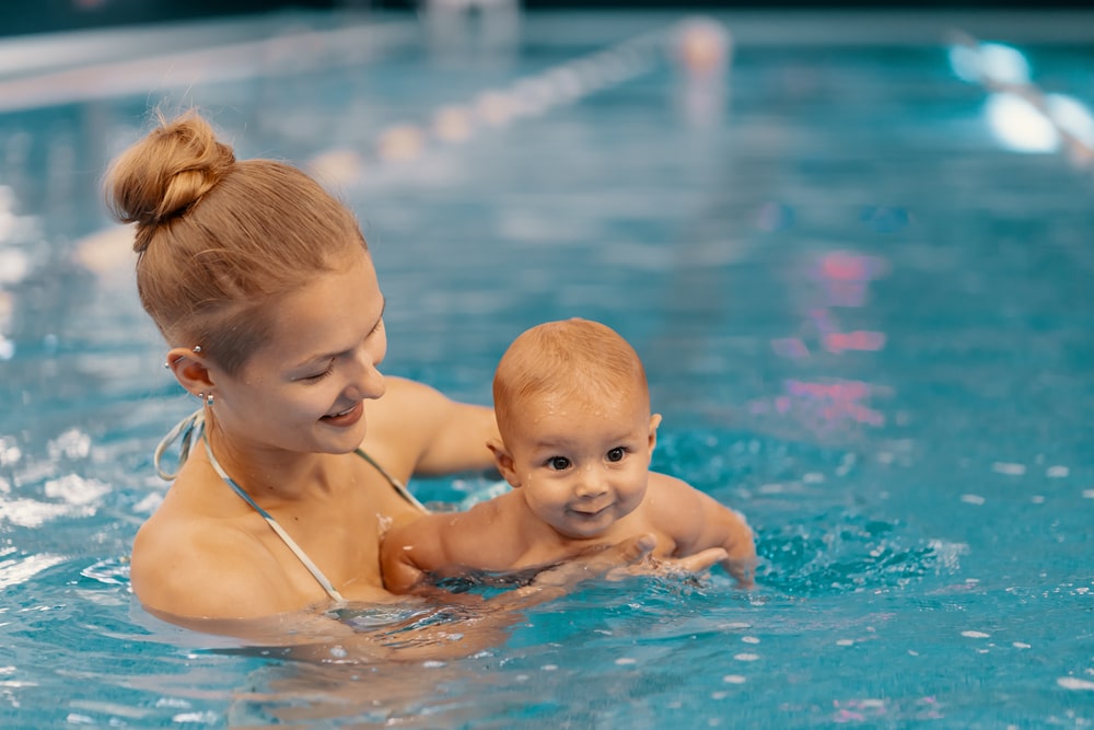 woman teaching baby to swim