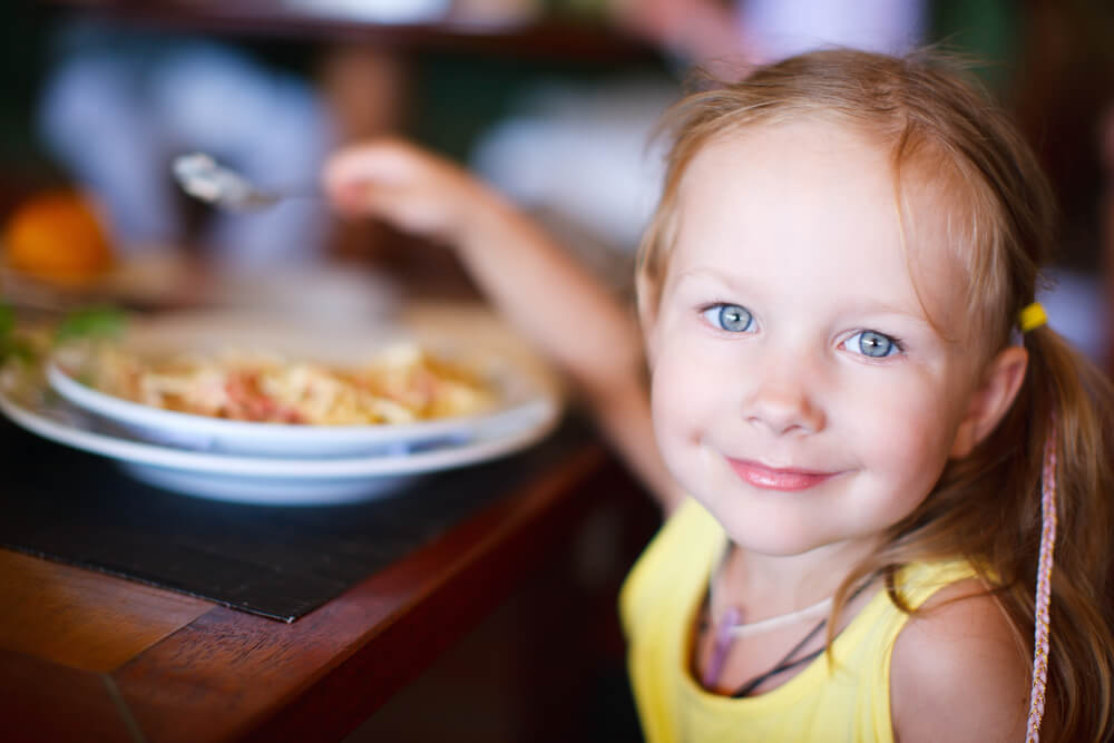 smiling girl with pasta dish at restaurant