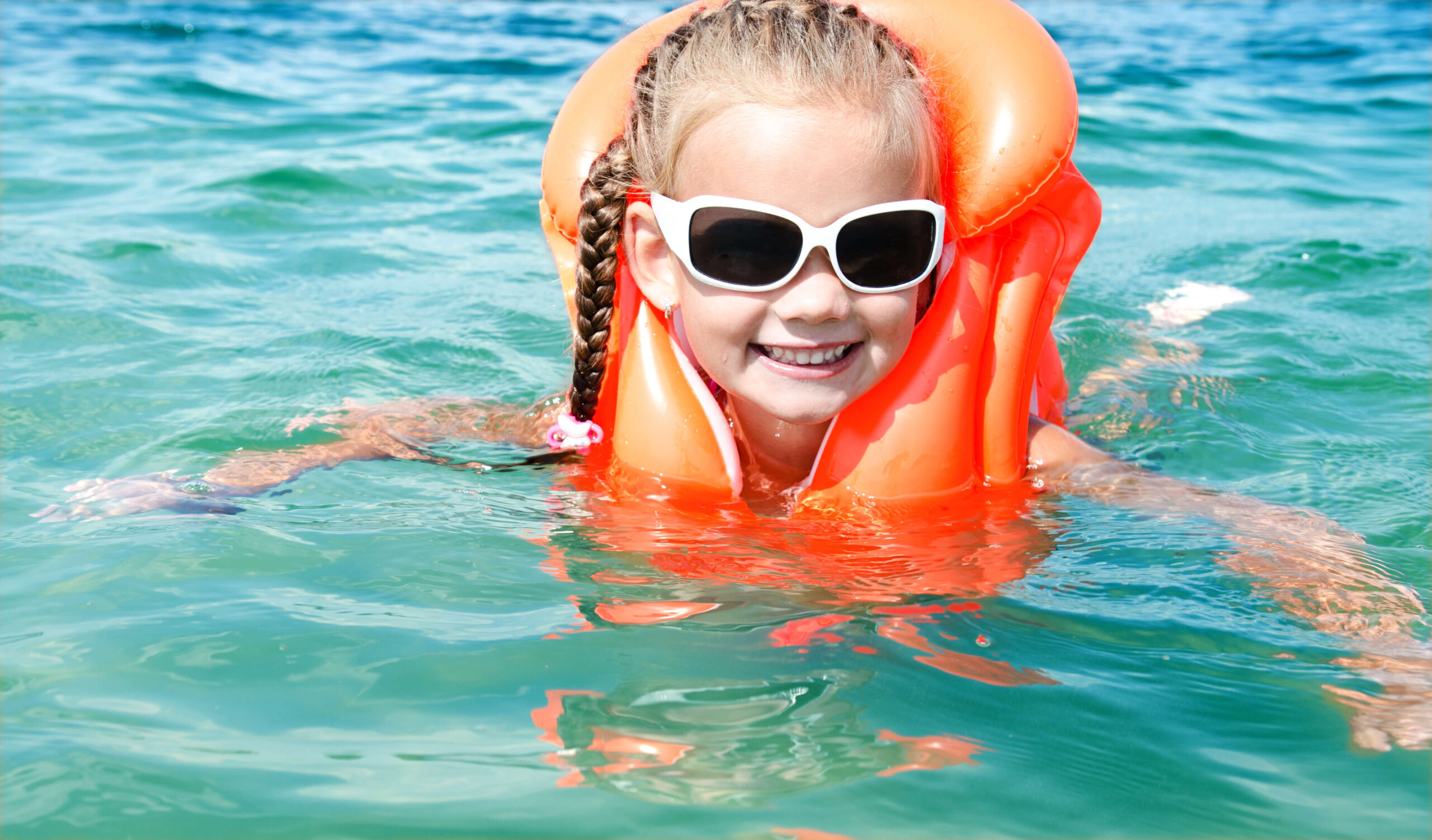 young girl in orange life vest in water