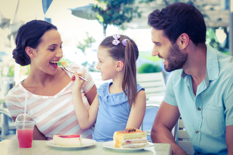 child feeding mom while dad watches