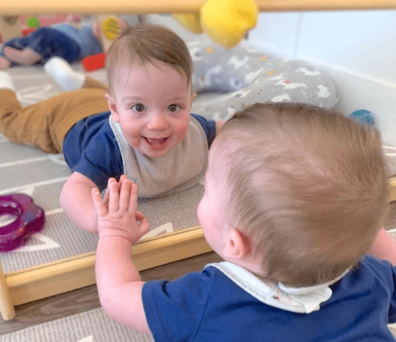 baby looking into mirror on floor