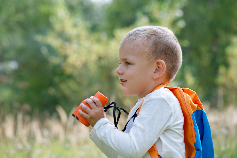 Young boy watching with binoculars of birds