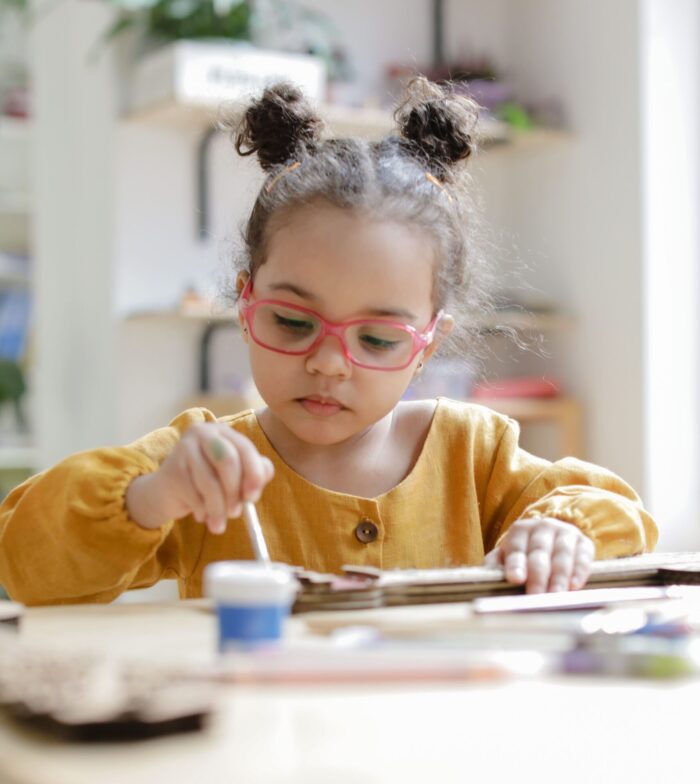 Hispanic toddler sitting at table and painting