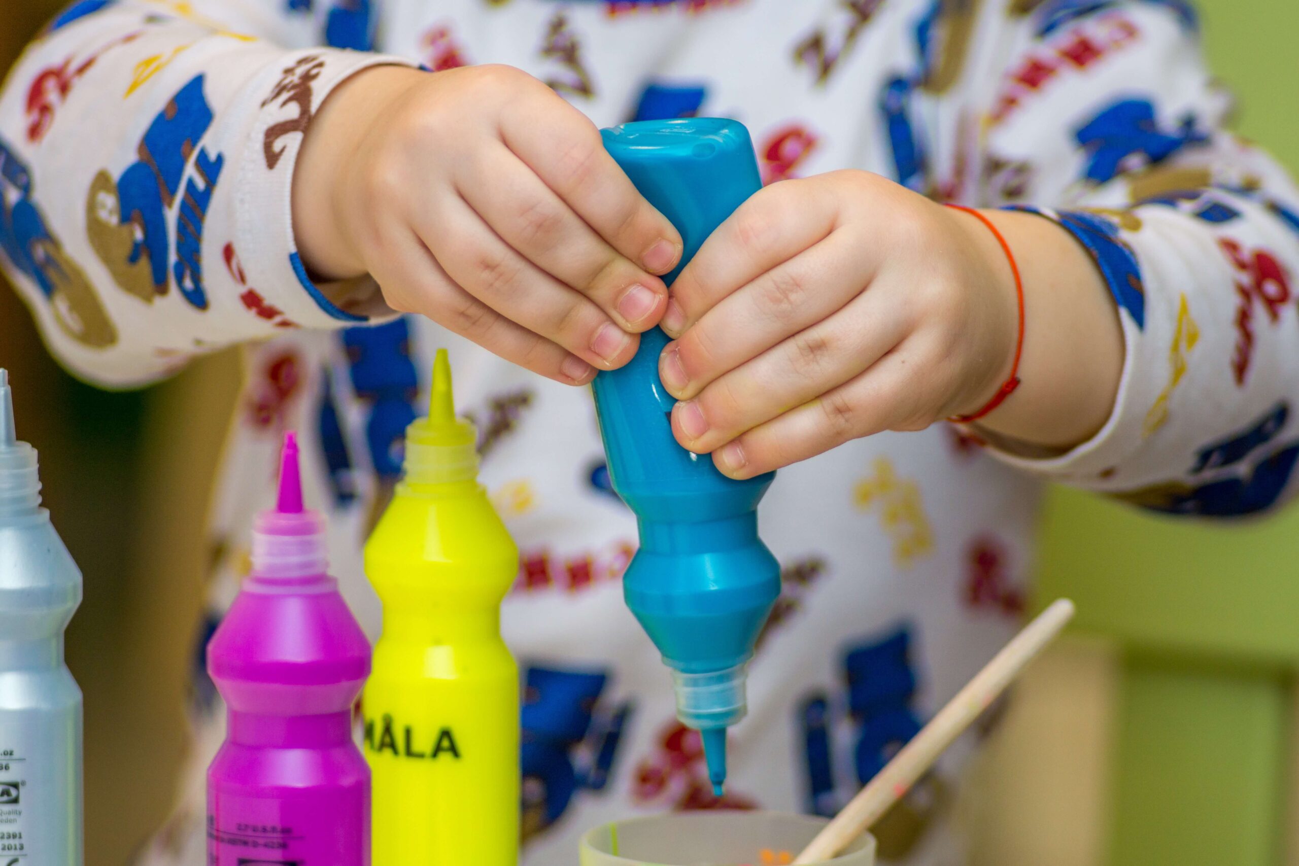 preschool child squeezing bottle of blue paint
