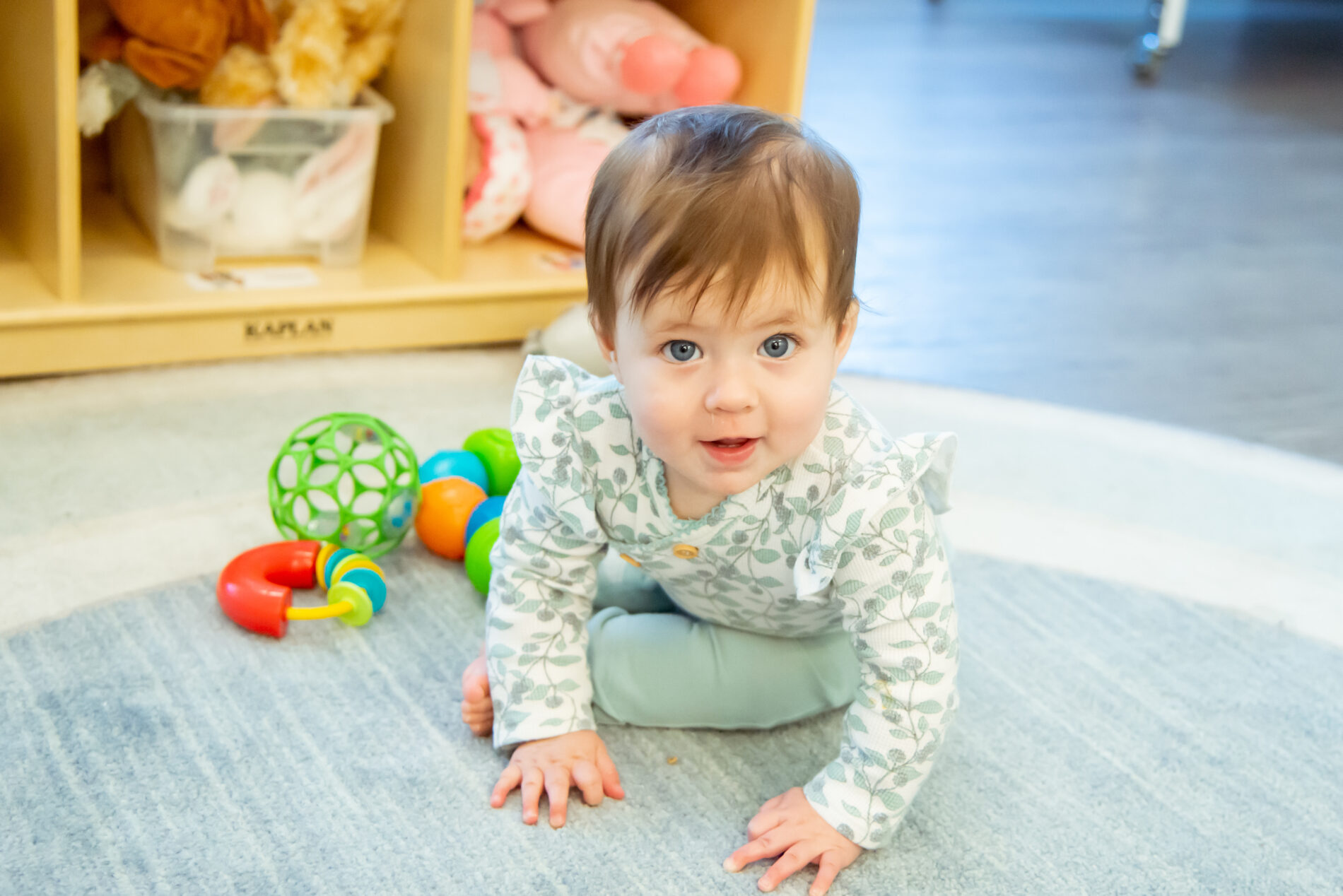 baby girl sitting on daycare floor looking at camera