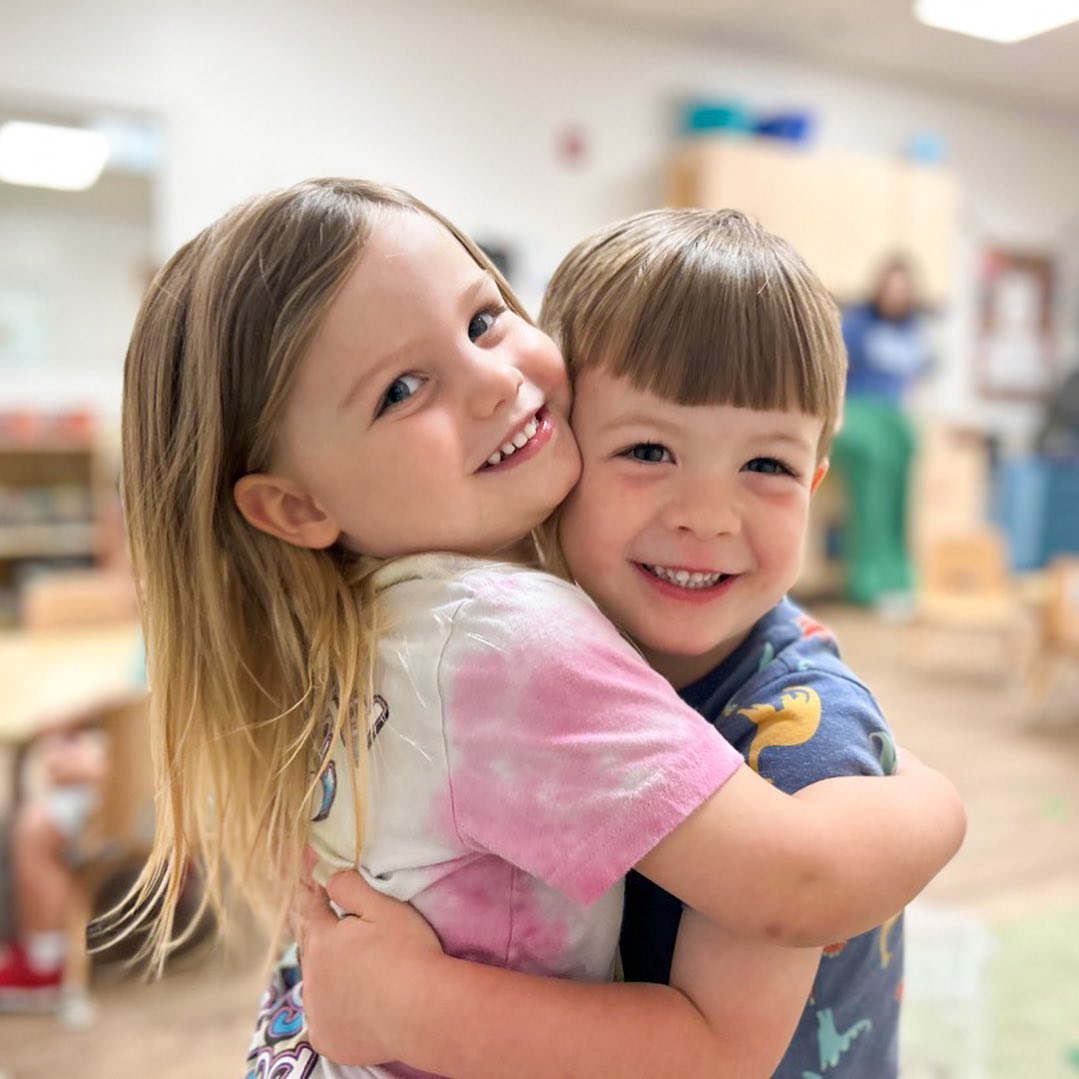 two preschoolers hugging each other in preschool classroom