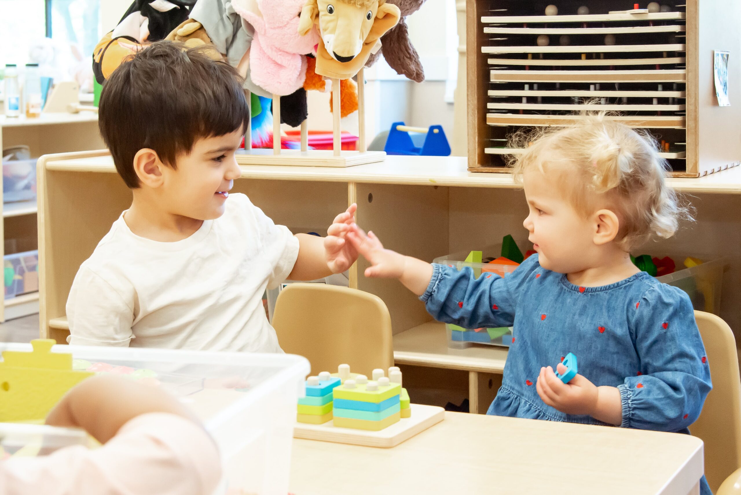 two preschoolers high fiving at a table
