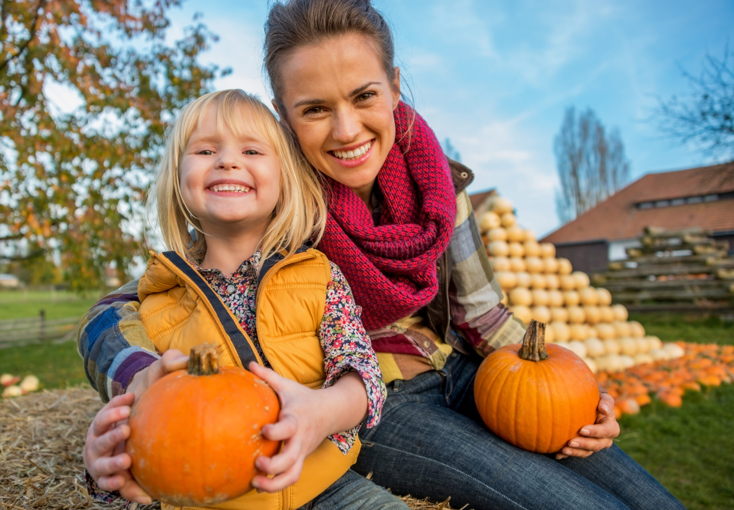 mom and daughter holding pumpkins in fall