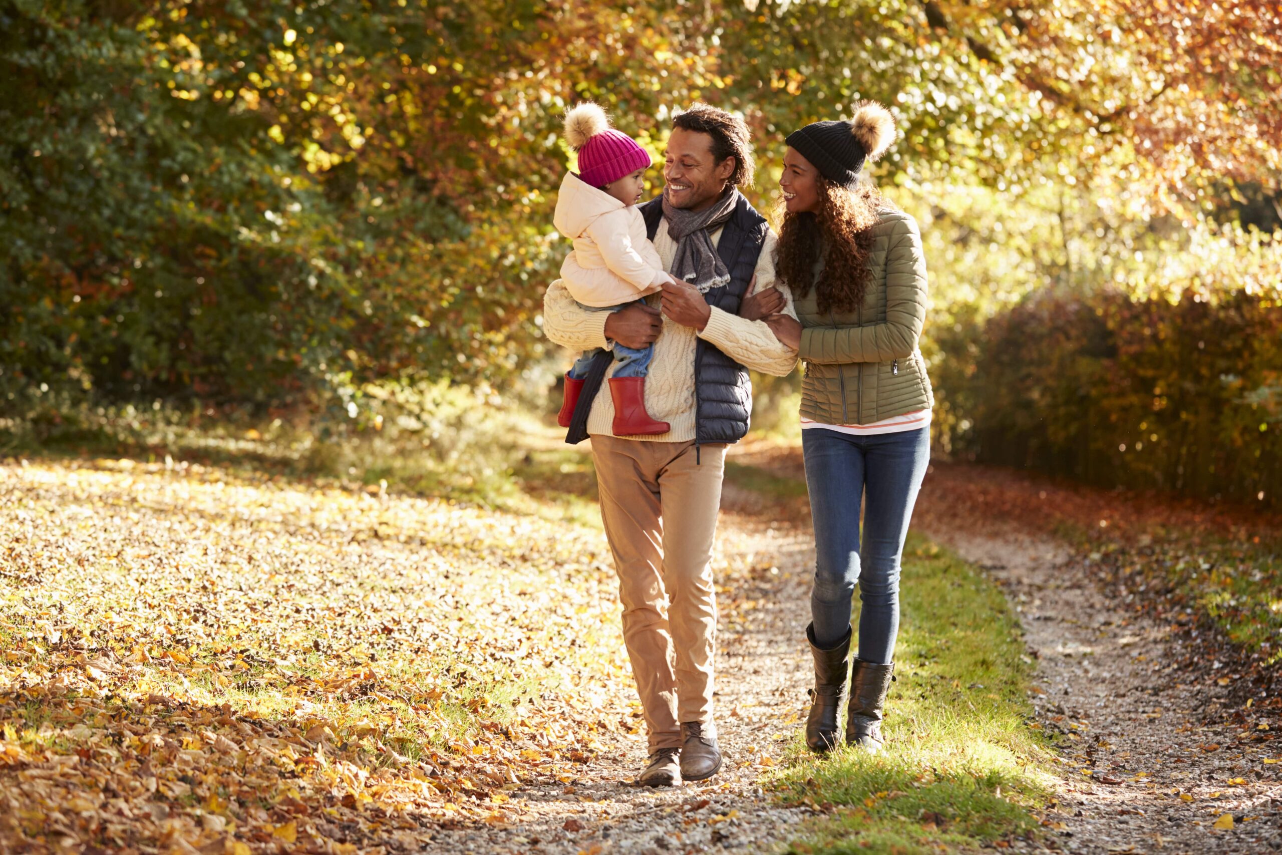 parents and child walking through autumn park path