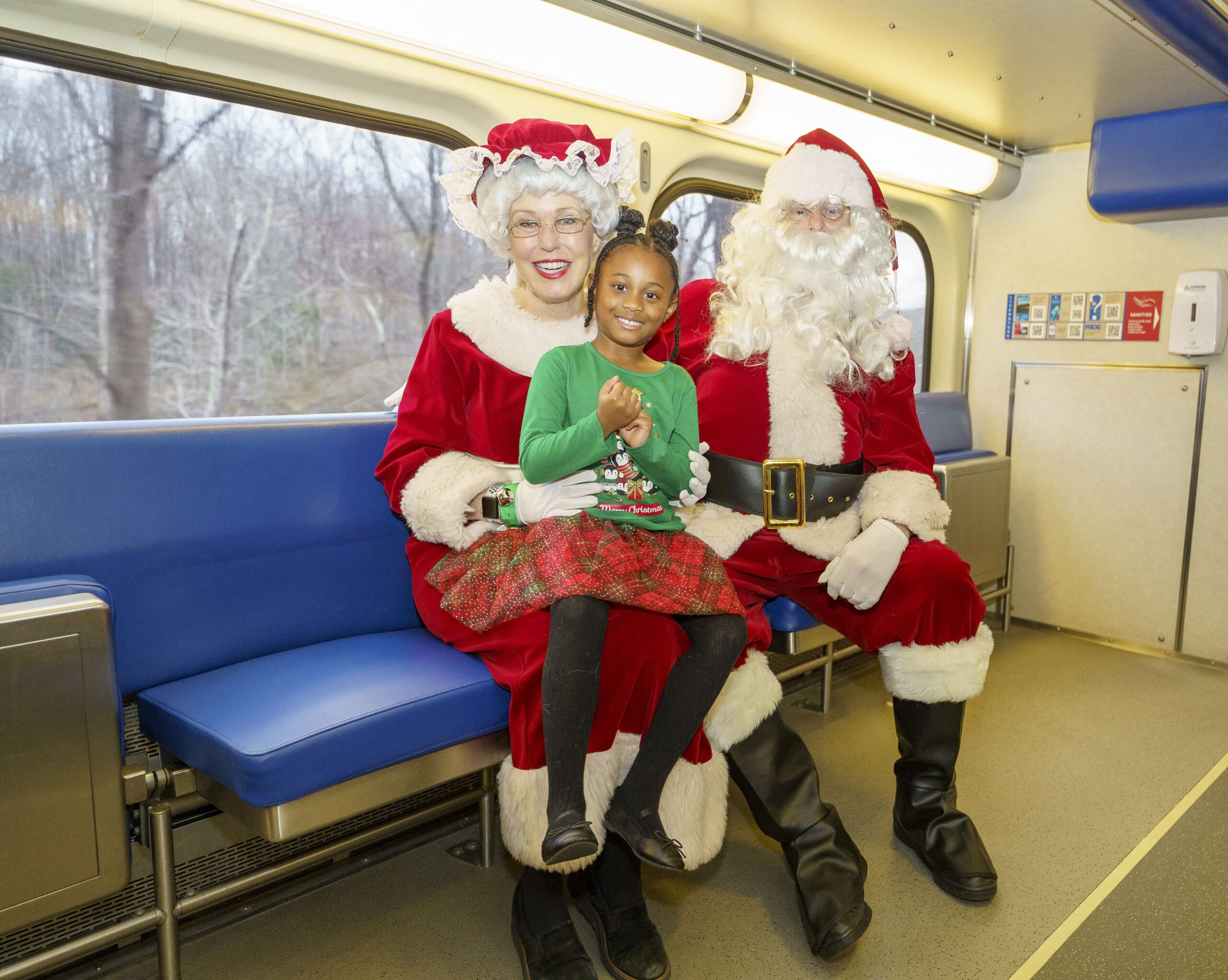 child sitting with Santa & Mrs Claus on a train