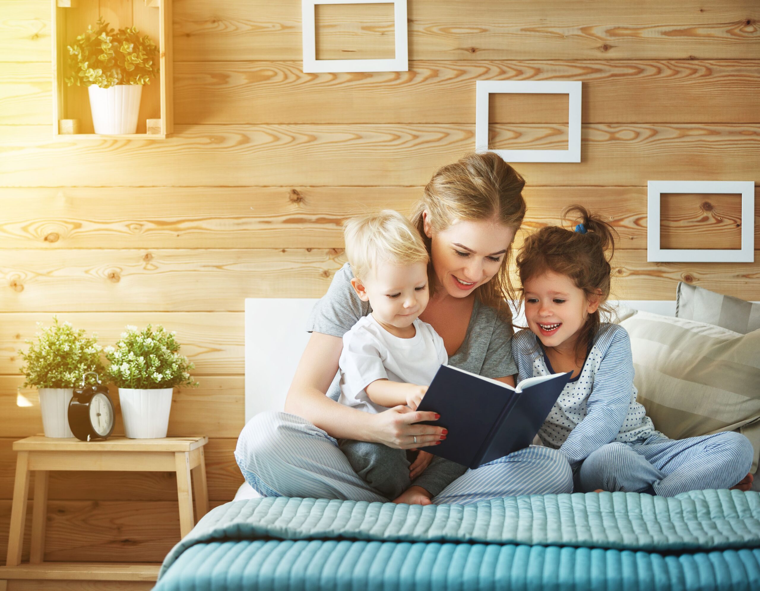 two children reading a book before bedtime with mom