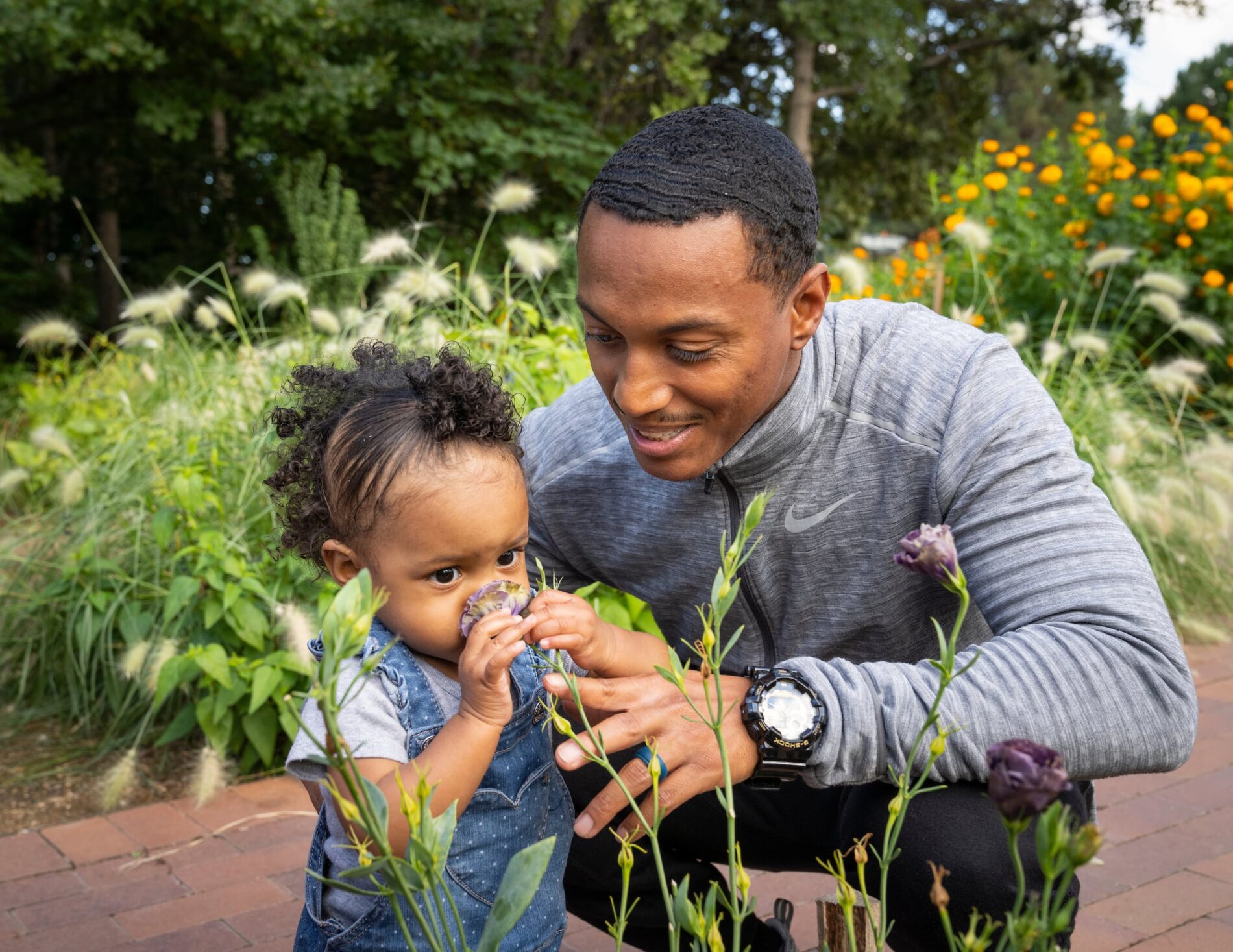 father and toddler daughter smelling flowers at Denver Botanic Gardens