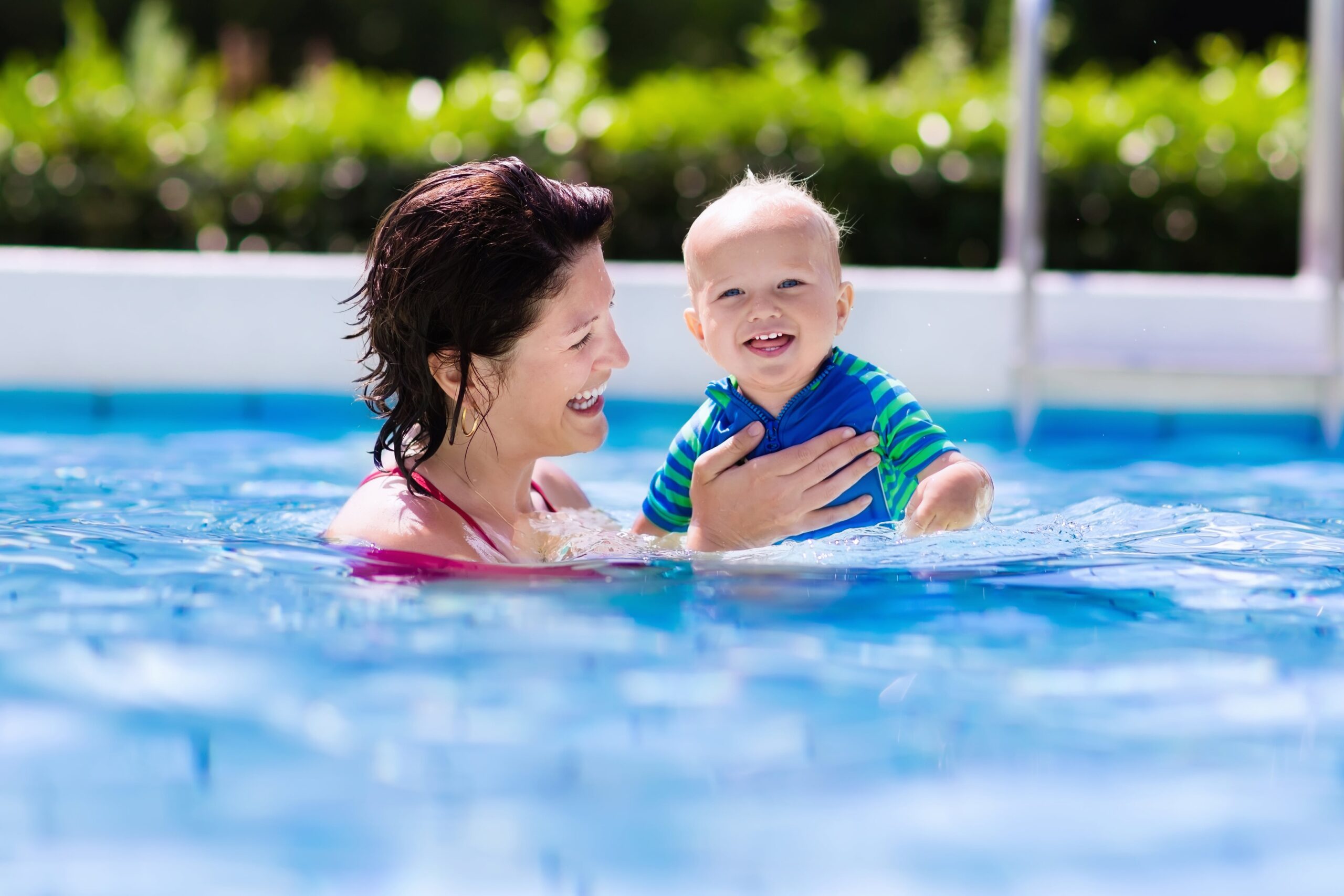 woman holding toddler in swimming pool for lessons