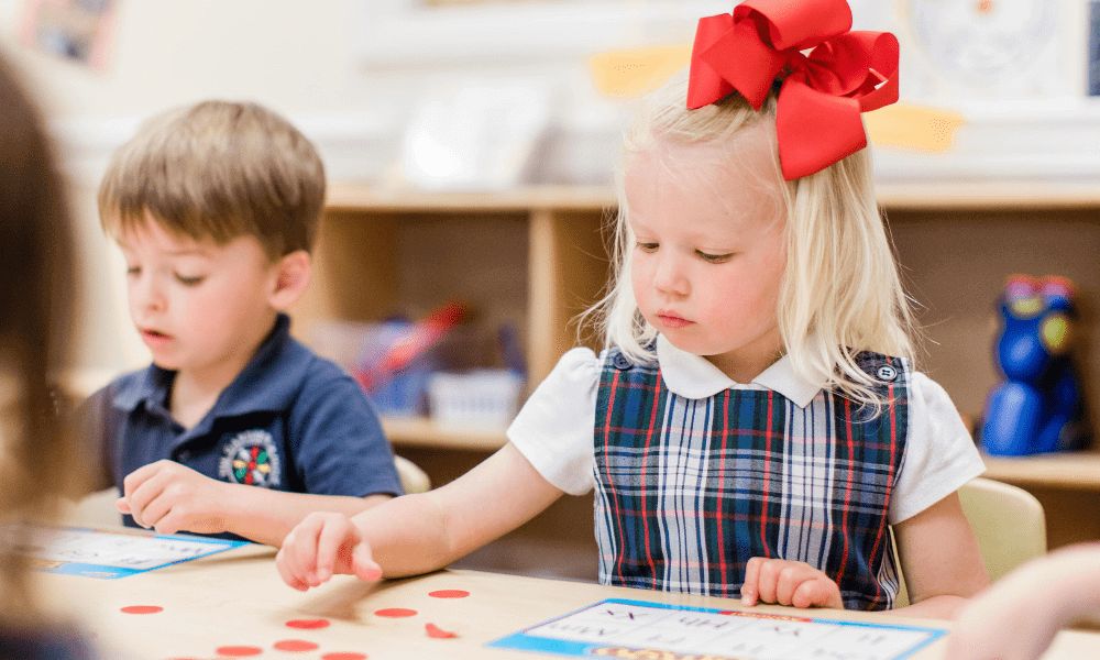 A girl in a big red bow playing bingo.