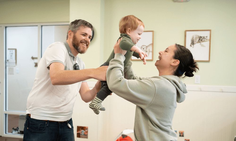 Parents playfully holding up their baby together.