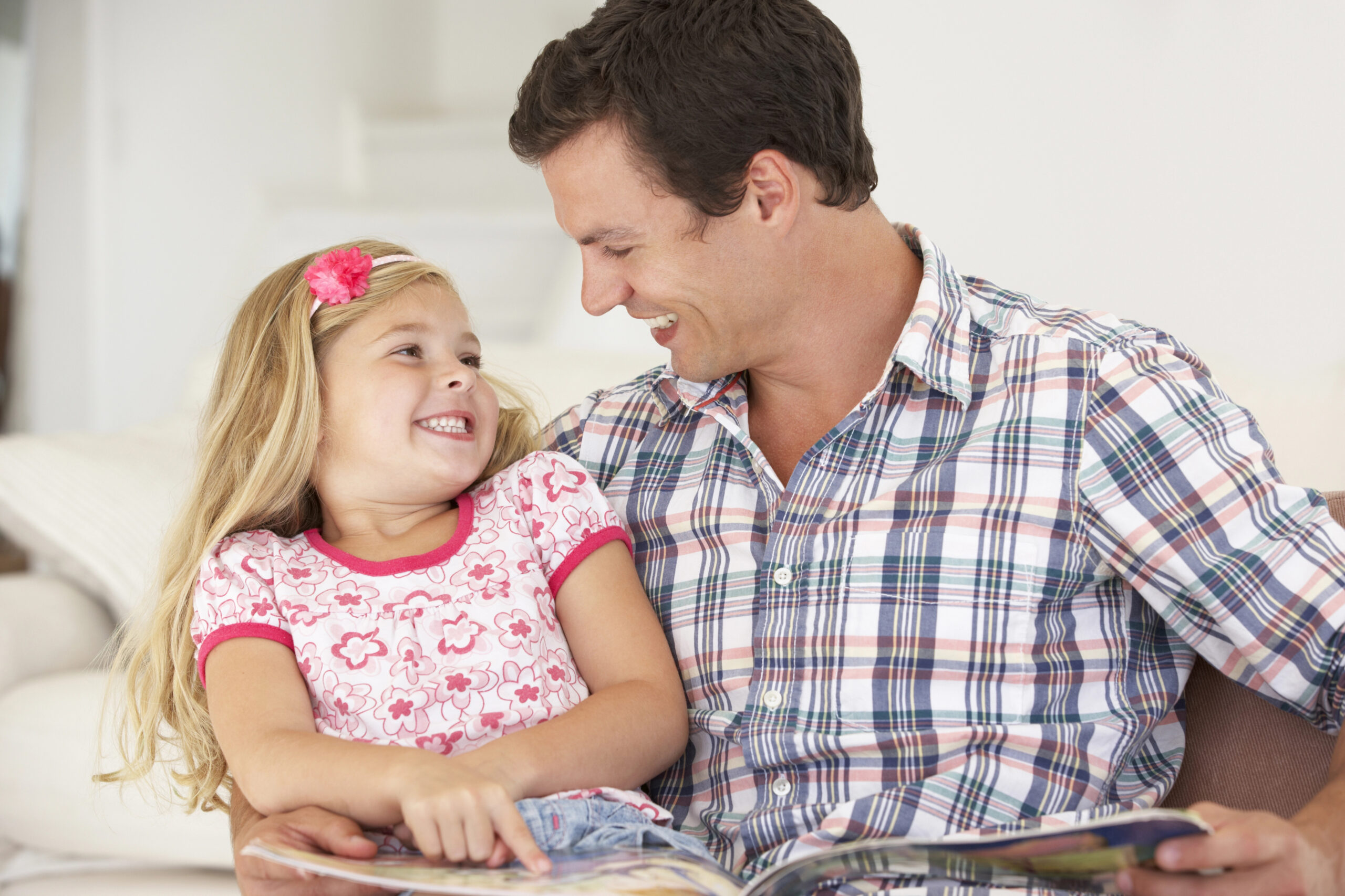 father reading a book to preschool daughter