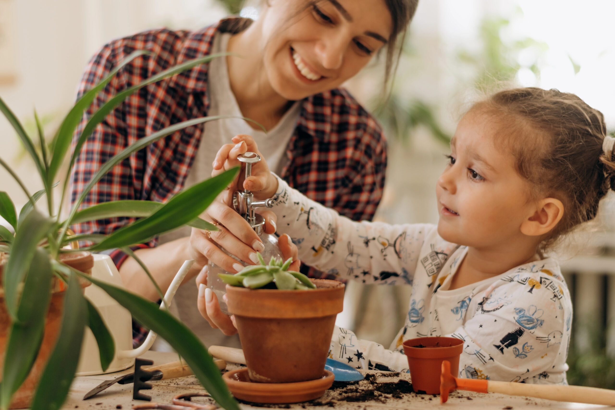 Mom and daughter watering small plant