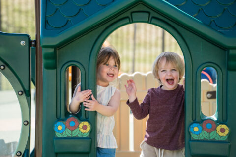 two preschoolers on playground in play house