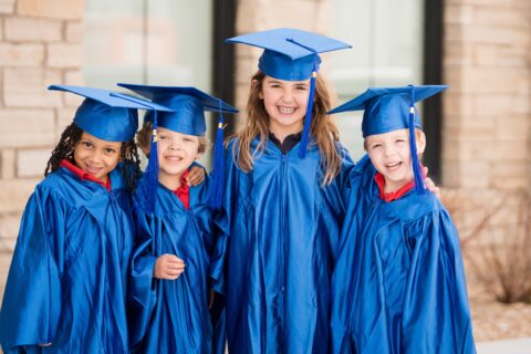 four preschool students in graduation gowns