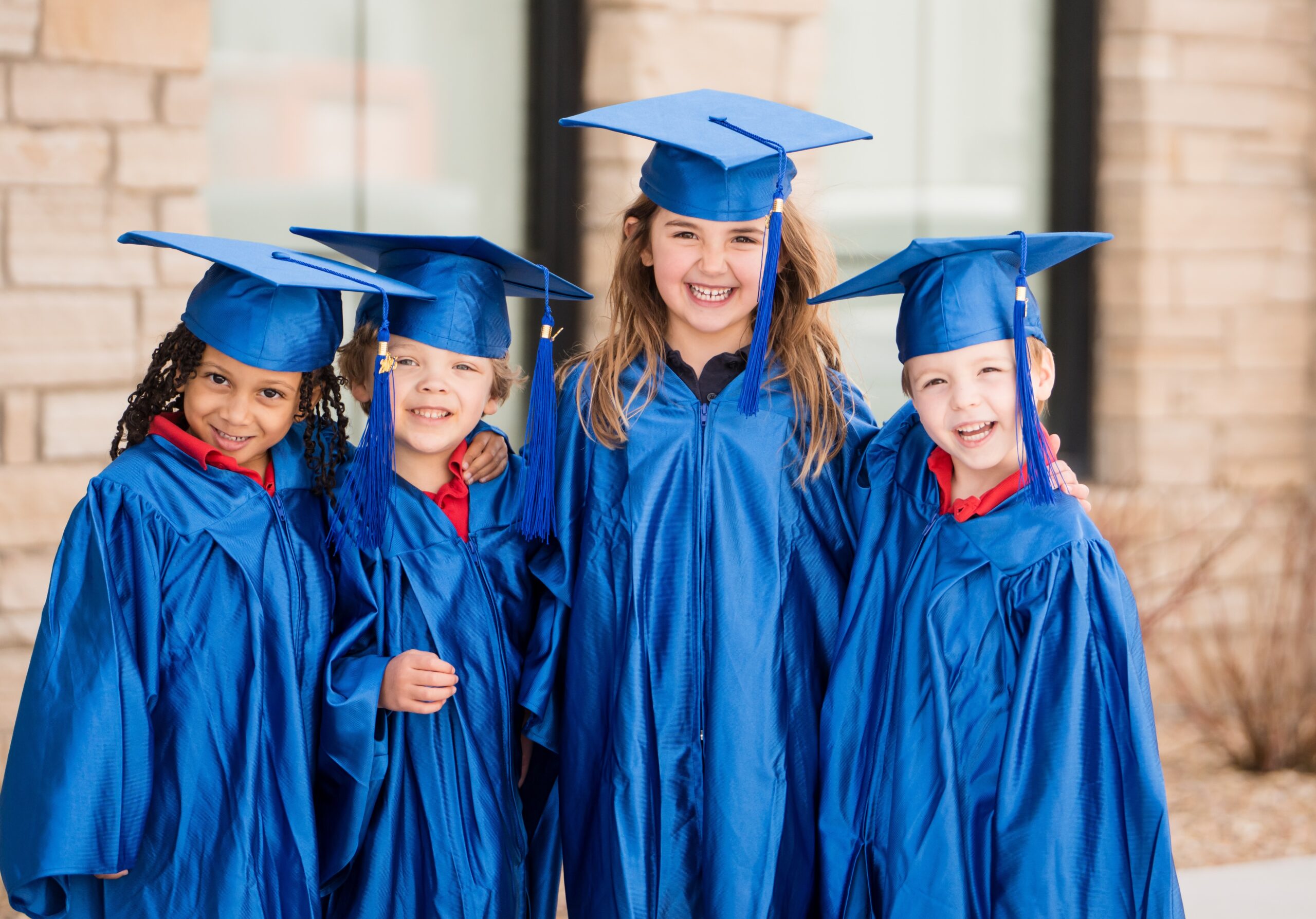 four preschool students in graduation gowns