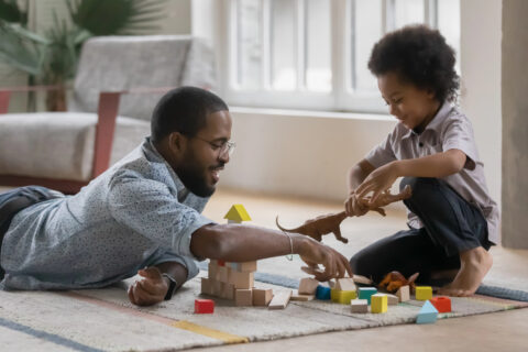 father and son playing with toys and blocks on rug