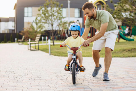 dad teaching child to ride a bike
