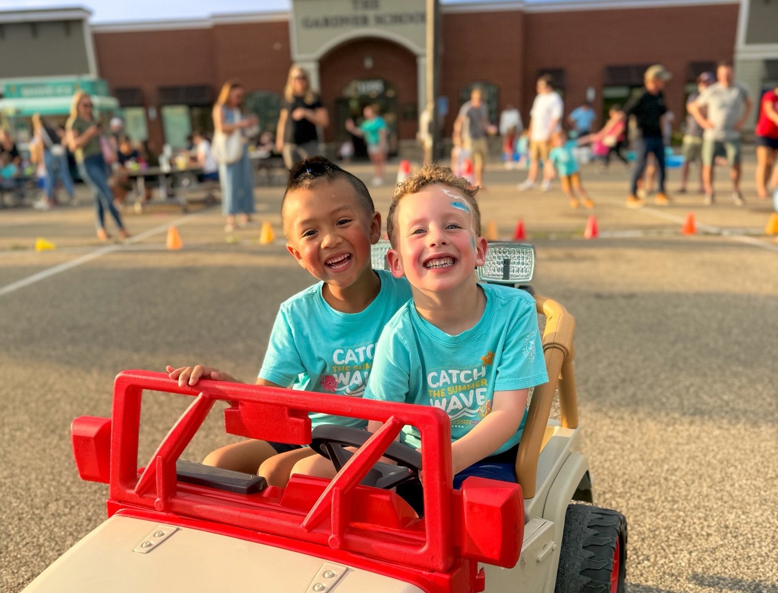 two students in toy jeep in front of school