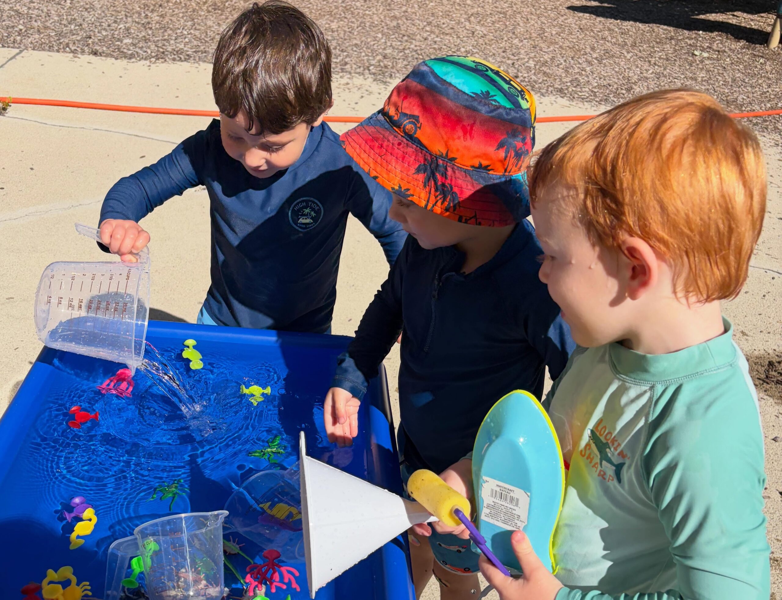 Three children playing with water sensory table